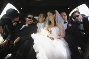 Hispanic newlyweds and family in limousine